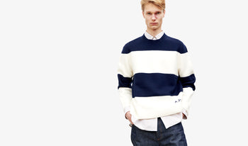 A.P.C. Men's Knitwear & Cardigans - Man wearing blue knit sweater and blue pinstripe pants standing in living room.