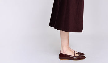 A.P.C. Women's Shoes - Woman wearing knit vest and blue jeans sitting on large couch.