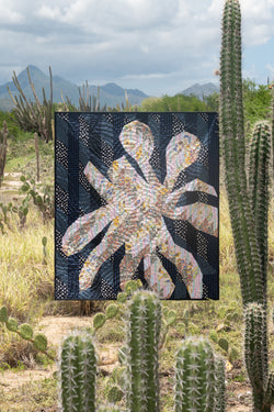 Quilt suspended among plants and cactus in a desert