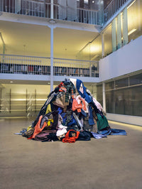 A.P.C. Recycling - a big pile of clothing in the middle of an office